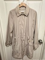 Full front view of beige Liz Claiborne trench coat on hanger