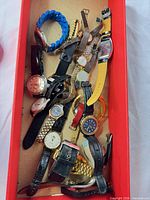 Watches piled in red box showing variety of straps and cases
