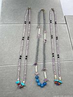 All three necklaces laid flat showing overall design and colors