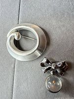 Both brooches front view on grey surface