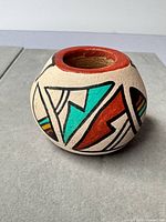 Front view of miniature painted clay pot