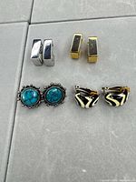 All four pairs of clip-on earrings displayed on grey surface