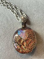 Full view of pendant showing multicolor iridescent surface and silver-tone bail on chain