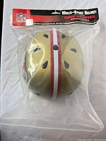 Helmet in sealed retail bag, full view showing gold shell and stripe