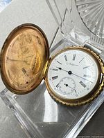 Open Niagara hunter-case pocket watch displayed on clear stand showing dial and inner cover