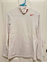 Front view of white Nike 49ers Dri-FIT mock neck pullover on hanger