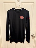 Full view of black long sleeve 49ers Nike Dri-FIT shirt on hanger