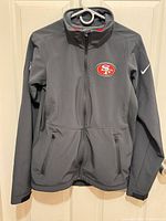 Front view of gray softshell jacket showing team logo and overall design