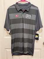 Front view of gray/black striped 49ers Crucial Catch Nike polo with tags attached