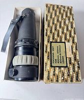 Focusing unit in box beside original Nikon patterned box lid