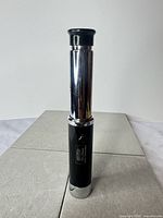 Full view of collapsed telescope standing upright, showing chrome and black finish