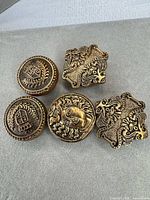 Group shot of five ornate brass buttons showing overall designs