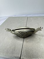 Full view of pewter dish showing dragon handles and repoussé sides