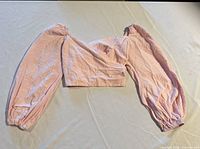 Full view of pink off-shoulder crop top laid flat showing overall design