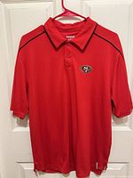 Front view of red polo shirt on hanger