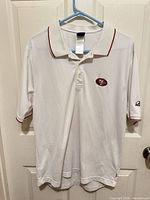 Front view of polo shirt on hanger showing overall design, collar, logos