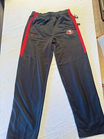 Full front view of charcoal and red 49ers track pants