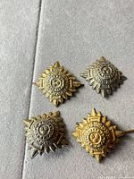 Front view of all four badges showing gold and silver tones