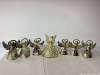 Front view of seven metal angel ornaments lined up