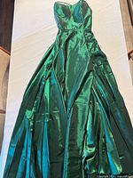 Full view of emerald satin ball gown laid flat