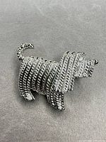 Front view of silver-tone dog brooch, detailing ribbed texture