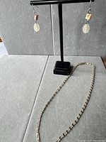 Necklace laid out and earrings hanging on stand