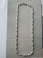 Full view of silver-tone bead necklace laid flat