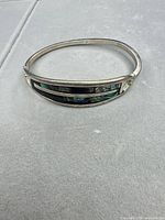 Top view of sterling hinged bangle showing abalone and onyx inlay