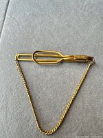 Front view of gold-tone Swank tie bar showing overall design and safety chain