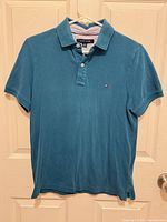 Front view of teal Tommy Hilfiger polo shirt hanging
