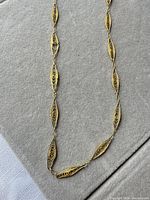 Close view of central filigree marquise links and gold finish