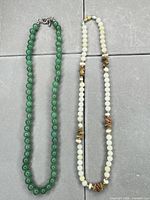 Both necklaces laid out flat showing full designs and clasps