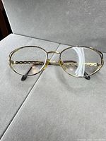 Front view of Valentino gold metal eyeglass frames resting on surface.