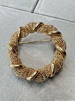 front view of circular gold-tone mesh wreath brooch