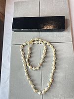 Full view of champagne baroque pearl necklace on display surface