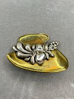 front view showing gold-tone base, silver floral motif, clear stones
