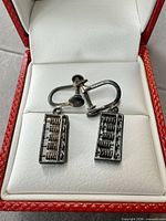 Earrings in box showing abacus charms and screw-back mechanism
