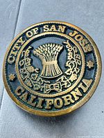 Front view of circular brass belt buckle showing full City of San Jose seal design and coloration