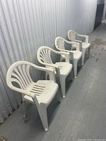 Front angled view showing four white plastic stacking armchairs lined up
