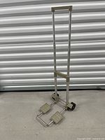 Front view of folded aluminum hand truck showing telescoping handle and wheels
