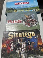 Top view of three board game boxes: Monopoly National Parks, Risk Global Domination, Stratego.