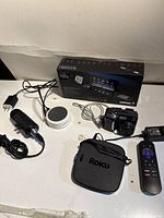 Full lot showing Nikon camera, Roku box with remote, smart speaker, car adapter, USB cable, Sharper Image Restore box