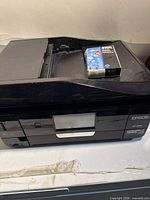 Front view of Epson XP-830 printer with ink cartridge on scanner lid
