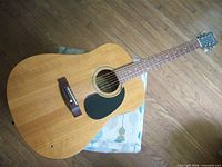 Full view of Hohner acoustic guitar on stool showing body, neck and headstock