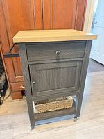 Full view of bar cart showing drawer, cabinet door, side handle, top and basket on lower shelf