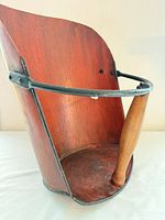 Front left view of red metal coal scuttle showing wood handle and black trim