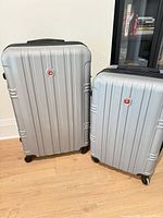 Front view of both silver SwissGear suitcases showing sizes and overall appearance