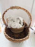 Overall view of large wicker basket holding smaller seagrass basket with rolled towels
