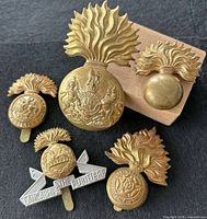 Five British Army grenade-style cap badges arranged for overview