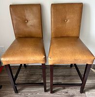 Front view of both stools showing upholstery, button tufting and leg frames